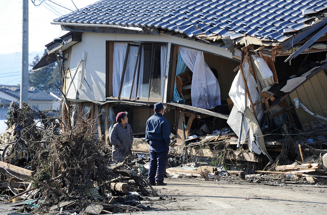 Local residents look at a damaged house